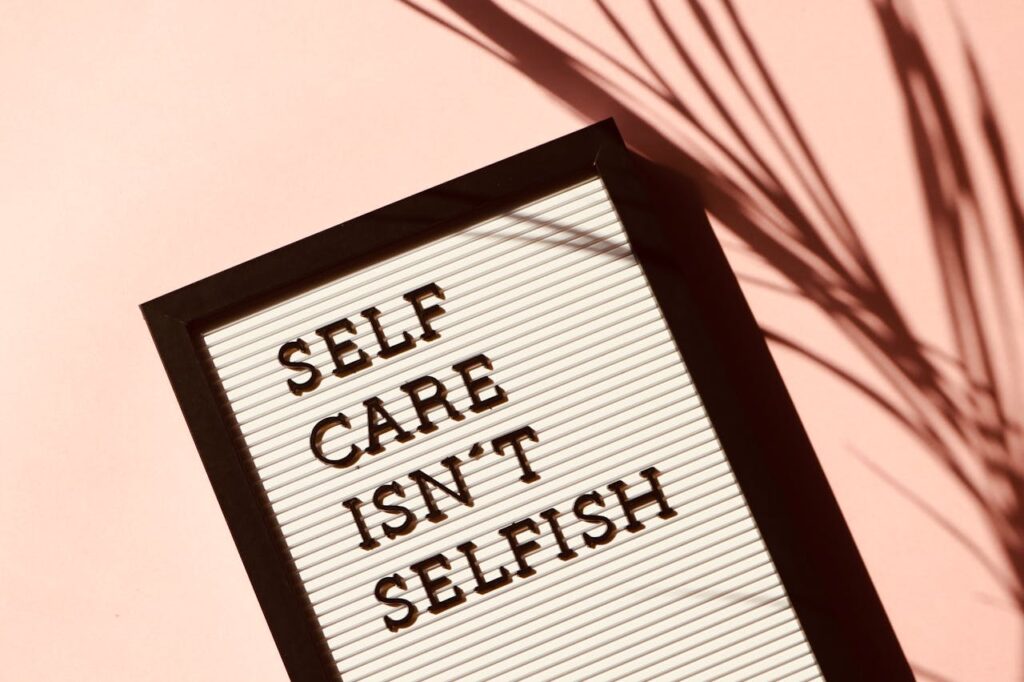 Mastering the First Impression: Your intriguing post title goes here Letter board displaying 'Self Care Isn't Selfish' with artistic shadow on pink background.